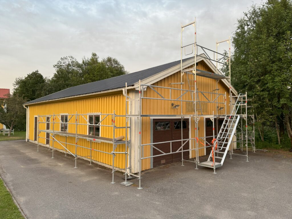 Bild på ett ställningsmontage framför ett större bilgarage.